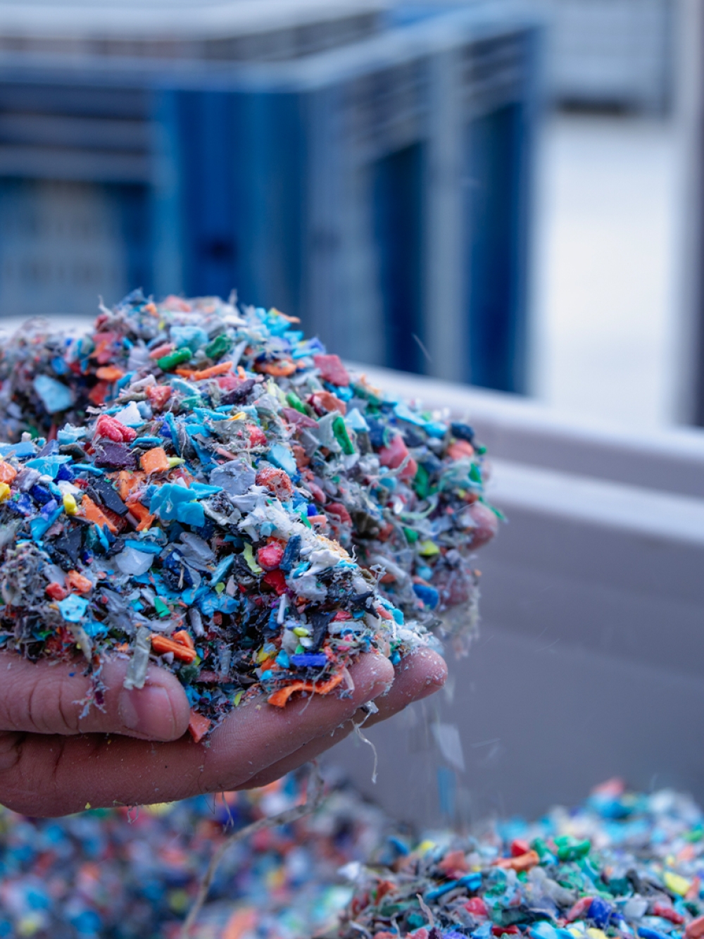 Main montrant une pile de copeaux de plastique dans un centre de tri