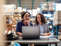 Deux femmes dans un entrepôt se questionnant devant un ordinateur