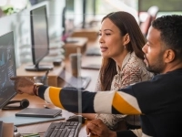 Deux collègues de travail regardant des graphiques sur un ordinateur de bureau